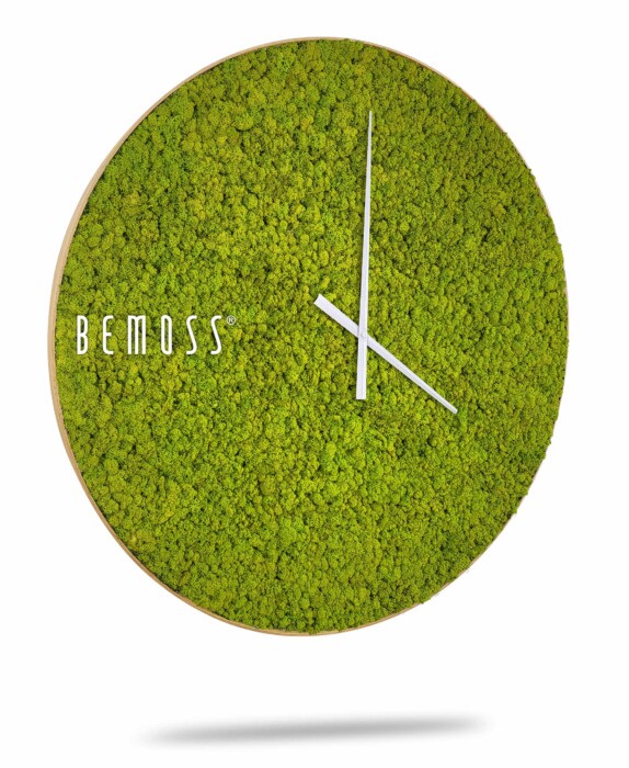 Une horloge murale moderne avec un design circulaire entièrement recouvert de texture de mousse verte, avec des aiguilles blanches élégantes et minimalistes en position croisée. 