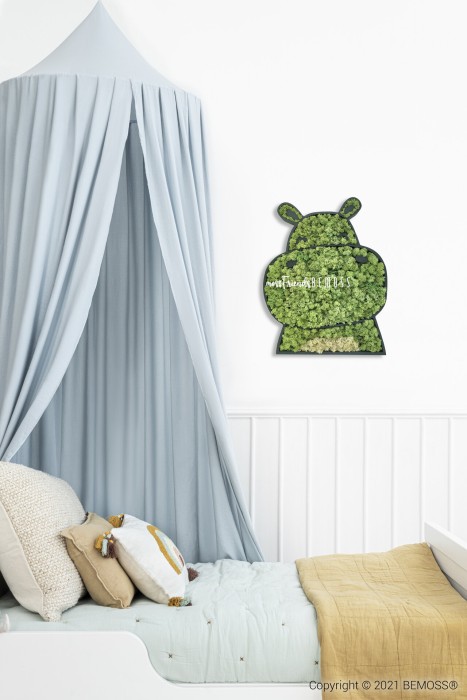 Une chambre d'enfant confortable comprend un baldaquin bleu au-dessus d'un lit avec une literie de couleur claire et des oreillers ludiques. Une tenture murale décorative murs végétaux, réalisée à partir de feuillage vert en forme de personnage de dessin animé, est suspendue au-dessus de la tête de lit.