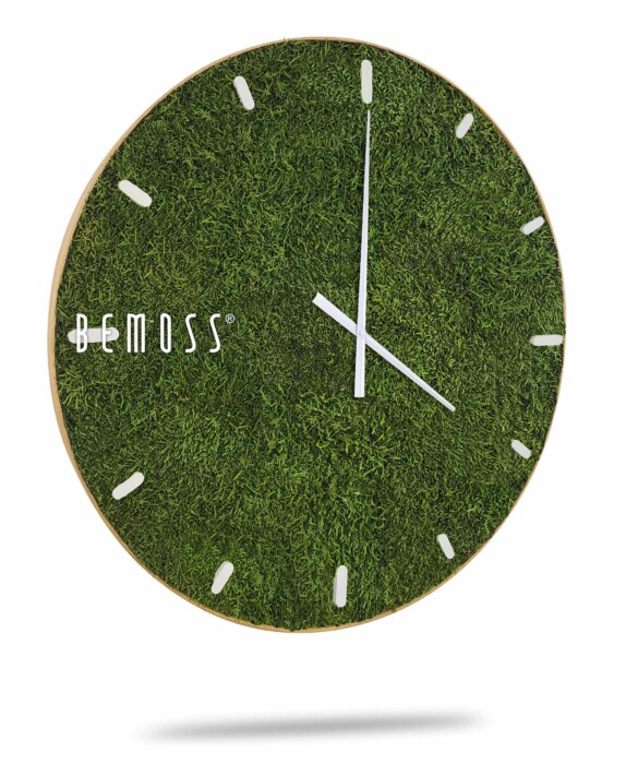 Une Horloge de mousse en mousse de RENNE avec cadran avec un cadran unique à texture d'herbe verte et des aiguilles blanches minimalistes des heures, des minutes et des secondes. L'horloge a des index blancs et le nom de la marque « BEMOSS » est affiché sur le côté gauche. Rappelant murs en mousse, cette montre élégante ajoute une touche naturelle à n'importe quel décor.