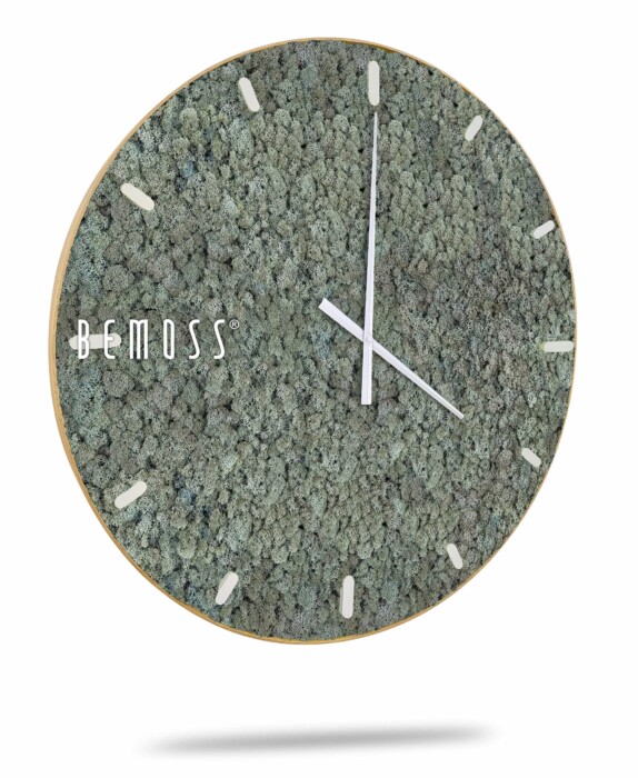 Une Horloge de mousse en mousse de RENNE avec cadran avec un cadran rond recouvert d'un matériau vert texturé ressemblant à de la mousse, ressemblant à un tableau de mousse. L'horloge comporte des index blancs minimalistes et des aiguilles blanches élégantes. Le nom de la marque « BEMOSS » est visible sur le côté gauche du cadran de l'horloge.