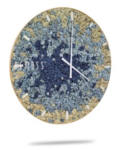 Une horloge murale dotée d'un cadran circulaire orné de textures complexes de mousse bleue, grise et beige apporte une touche d'élégance naturelle à vos murs en mousse. Les aiguilles et les index de l'horloge sont blancs et se détachent sur le fond texturé. Le nom de la marque « BEMOSS » est imprimé en blanc sur le côté gauche du cadran de l'horloge.